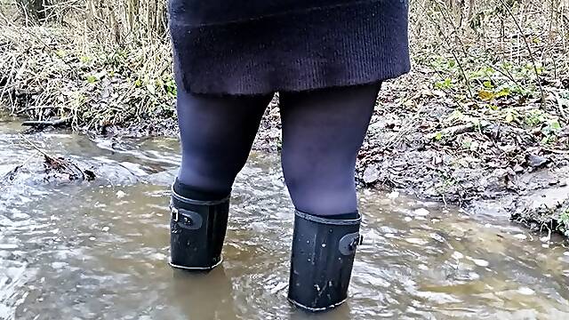 Black rubber boots and a deep stream